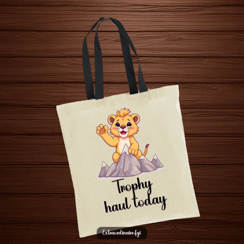 Funny lion cub explorer tote bag, showing a cub raising paws after conquering miniature mountains.